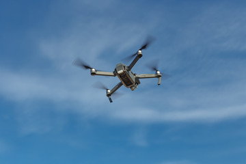 Drone with digital camera, hovering in blue sky, copy space.