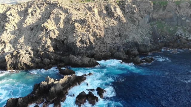 aerial footage of volcano stones in the sea with waves and a cliff in Tenerife in a natural swimmingpool