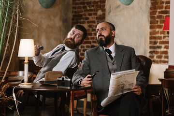 Two bearded men wearing old fashioned suits talking or discuss something in the restaurant