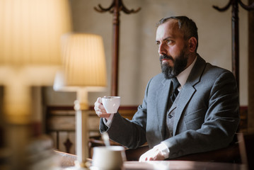 Bearded middle age man in retro suit sitting at the restaurant