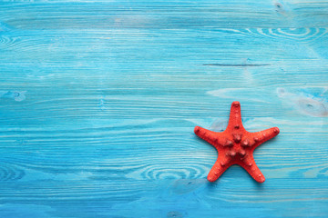 Fototapeta na wymiar Summer sea vacation concept background with copy space. Red starfish on a blue wooden floor background.
