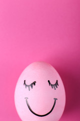 Pink egg with painted smiles. Happy Easter concept greeting card design.