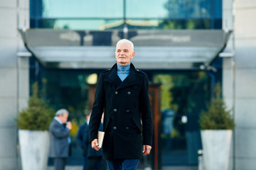 Old man with a notebook walking at the street