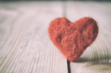 red heart handmade of wool on wooden background, a symbol of love, bright sun background