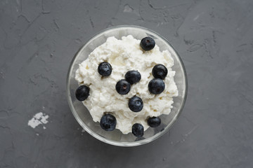 natural cottage cheese with berries for Breakfast in a glass bowl on a gray background