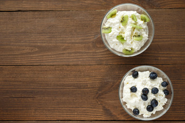 cottage cheese with blueberries and kiwi on wooden background