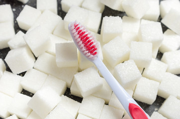 toothbrush on the background of the sugar cubes of refined sugar, preventing tooth decay, caring for the health of your teeth, the causes of caries