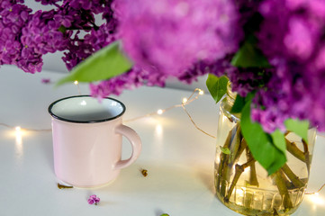 Lilac bouquet on the table with cups and festive lights