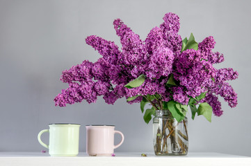 Lilac bouquet on the table with cups 