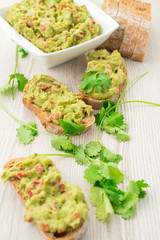 Fresh avocado cream or guacamole on wholemeal slices, healthy breakfast concept.