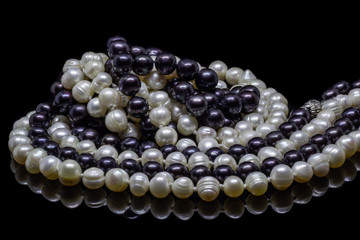 Two mixed strands of natural black pearl beads on a black background with reflection