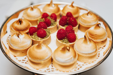 Tart with lemon curd and meringue and raspberry pistachio cake on some festive event, party or wedding reception