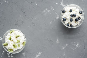 Cottage cheese with kiwi and blueberries on cement background with copy space, Flat lay, HLS.