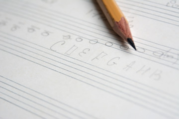 pencil on a musical notebook close-up, abstract musical notes and chords, musical background