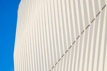 Wave facade of the building. White graphical linear facade of the building. The play of light and shadow. Neutral fashionable background. Light stripes.