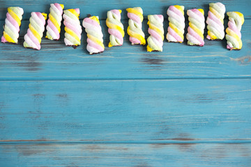 Marshmallows on a blue wooden background. Background with sweets. Design frame for text with marshmallows