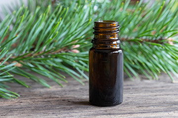 A bottle of pine essential oil with pine branches