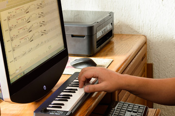 Compositor trabajando en computadora con teclado musical