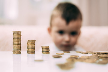 Junge schaut sich Geldstapel an, die auf einem Tisch liegen