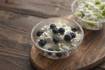 Still life with cottage cheese blueberries and kiwis on wooden stand copy space