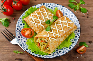 Fototapeta na wymiar Crepes stuffed with stewed cabbage with carrots and eggs.