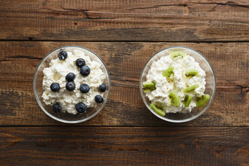 natural cottage cheese with berries and fruit for Breakfast in glass bowl on wooden background. healthy Breakfast