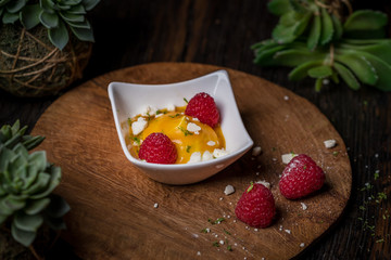 Cream fruit dessert with mango passion fruit sauce and raspberries and meringue 