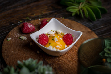 Cream fruit dessert with mango passion fruit sauce and raspberries and meringue 