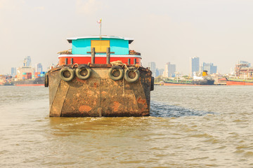 Large shipping barge upstream along Chao Phraya River in Bangkok, Thailand.