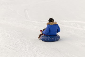 winter, leisure, sport, friendship and people concept - group of happy people sliding on the snow...