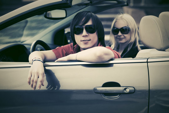 Happy Young Couple Driving Convertible Car