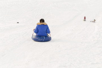 Fototapeta na wymiar winter, leisure, sport, friendship and people concept - group of happy people sliding on the snow inflatable chambers