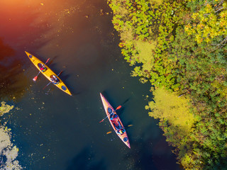 Aerial drone bird's eye view photo of Happy family with two kids enjoying kayak ride on beautiful river. Little boy and teenager girl kayaking on hot summer day. Water sport fun. - obrazy, fototapety, plakaty