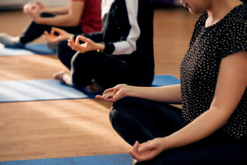 Calm, healthy and wellness lifestyle relax concept. Young girls practicing yoga lesson with instructor in indoor gym studio. Sitting in Sukhasana exercise, easy seat pose. Meditation in lotus position