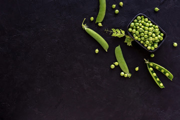 Fresh green peas in  bowl on black stone background. Top view