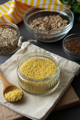 Raw millet groats in glass bowl with variouse cereals on the background. Healthy food, cereals. Uncooked cereals for breakfast.