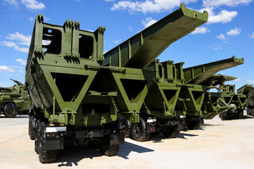 Military mechanized bridges in row, army engineering equipment, heavy industry, white clouds and blue sky on background