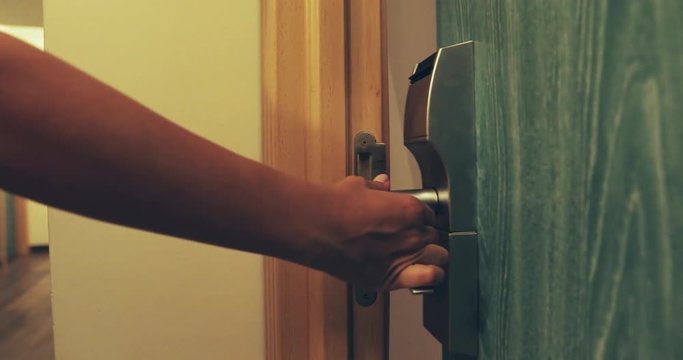 A woman opens the door with a key card and enters the room.