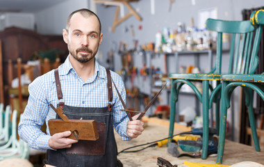 Carpenter standing in furniture repair shop