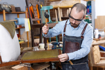 Craftsman reupholstering chair in workshop