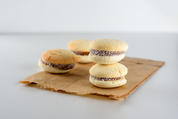Delicious Argentinian cookies alfajores with cream dulce de leche close-up on the plate. White vanilla macaroons on white background. French delicate dessert for Breakfast in the morning light.