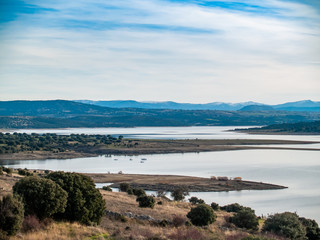 Landscape of a reservoir and mountains in a day with fog and clouds and birds swimming and flying in in La Maya Reservoir (Salamanca)