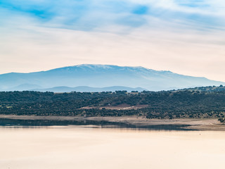 Landscape of a reservoir and mountains in a day with fog and clouds and birds swimming and flying in in La Maya Reservoir (Salamanca)