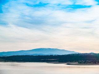 Landscape of a reservoir and mountains in a day with fog and clouds and birds swimming and flying in in La Maya Reservoir (Salamanca)