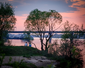 Fototapeta na wymiar Romantic cople on the river bank, sunset