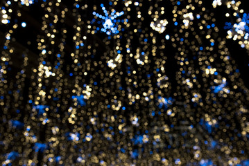 Obraz premium festive blurred urban bokeh background with glowing garlands of yellow and blue against night sky