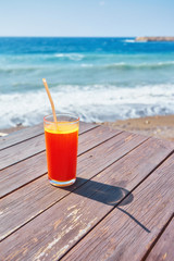 Orange cocktail on wooden table. Sunny day near mediterranean sea.