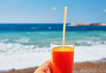 fresh drink in man's hand on the background of the exotic beach