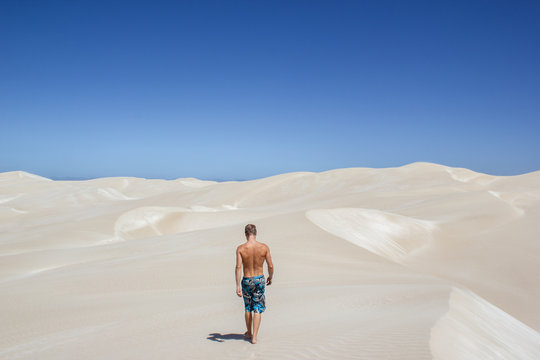 young man walking on endless and wide sand dunes under a beautiful sky with clouds, Nullabor Dessert, Australia