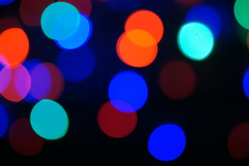 Multi-color blue holiday garland. Garland is blurred. Many big colorful round lights. Fully defocused photo. Blurred background and foreground. Holiday mood. New Year and Christmas is coming.